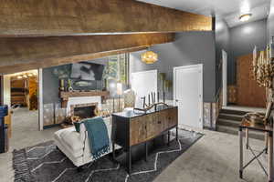 Carpeted living area with a chandelier and a fireplace with raised hearth