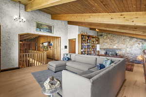 Living room featuring a chandelier, hardwood / wood-style floors, and wooden ceiling with exposed beams