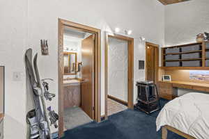 Bedroom featuring a textured wall, carpet, and a sink