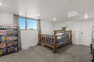 Bedroom with a wall mounted air conditioner, carpet floors, a textured ceiling, recessed lighting, and baseboards