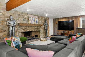 Living area featuring a fireplace, a textured ceiling, and wooden walls