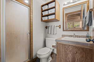 Bathroom featuring a stall shower, vanity, and toilet