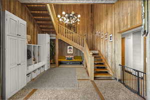 Stairway featuring wood walls and a chandelier