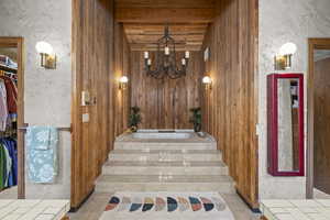 Stairway featuring a chandelier, a textured wall, and beamed ceiling