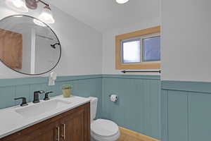Bathroom featuring toilet, vanity, a wainscoted wall, and wood finished floors