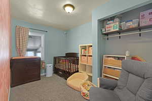 Bedroom featuring carpet and a crib