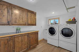 Washroom featuring cabinet space, washer and dryer, light wood finished floors, recessed lighting, and baseboards