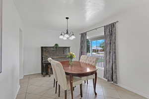 Dining area with a chandelier, light tile patterned floors, and baseboards