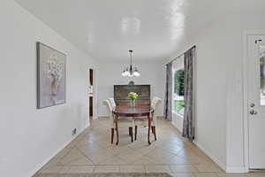 Dining area featuring a chandelier, light tile patterned floors, and baseboards