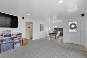 Carpeted living room with tile patterned floors, a chandelier, baseboards, and recessed lighting
