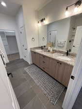 Bathroom with tile patterned floors, double vanity, a closet, and a shower