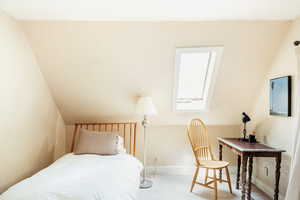 Carpeted bedroom with vaulted ceiling and baseboards