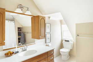 Bathroom featuring lofted ceiling, tile patterned floors, vanity, and toilet
