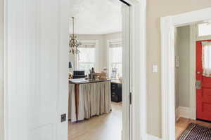 Hall featuring light wood finished floors, a textured ceiling, and a chandelier