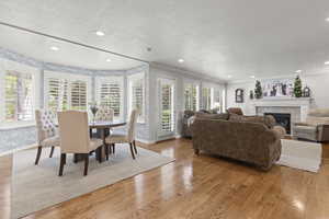 Dining area with plenty of natural light, baseboards, a tiled fireplace, light wood-style flooring, and a textured ceiling