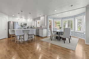 Dining area with recessed lighting, a textured ceiling, light wood-style floors, baseboards, and wallpapered walls