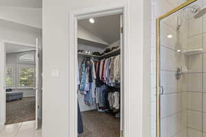 Spacious closet with vaulted ceiling and light colored carpet