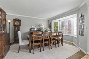 Dining room with crown molding, carpet, and baseboards