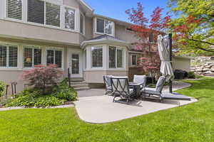 Rear view of property with stucco siding, entry steps, a patio, and a yard