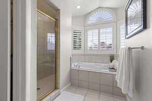 Bathroom with tile patterned flooring, a stall shower, a garden tub, and lofted ceiling