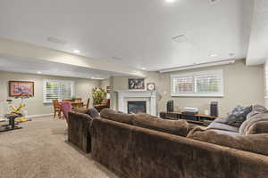 Living area with light colored carpet, a tile fireplace, recessed lighting, a textured ceiling, and baseboards