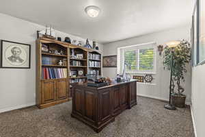 Office space featuring dark carpet and a textured ceiling