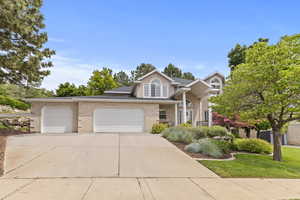 View of front facade with a garage, driveway, a front yard, and brick siding