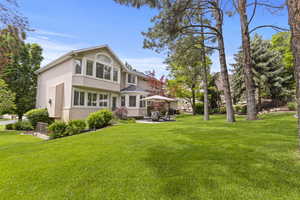 Rear view of property featuring stucco siding, a yard, and a patio