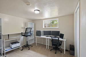 Carpeted home office with baseboards and a textured ceiling