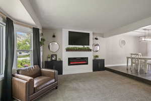Living area featuring carpet, a large fireplace, and baseboards