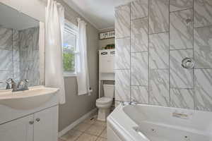 Full bath with vanity, toilet, tile patterned floors, baseboards, and a combined bath / shower with jetted tub