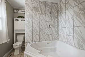 Bathroom with toilet, tile patterned flooring, baseboards, and a combined bath / shower with jetted tub