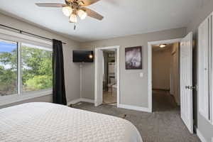 Bedroom featuring carpet flooring, baseboards, ensuite bath, and ceiling fan