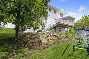 Rear view of property with a wooden deck, stairway, and a playground