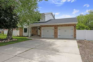 View of front facade with an attached garage, concrete driveway, brick siding, board and batten siding, and a shingled roof