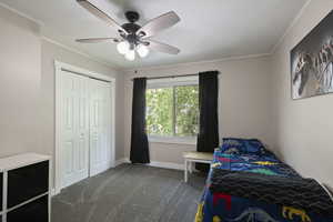 Bedroom featuring dark carpet, baseboards, crown molding, a closet, and a ceiling fan