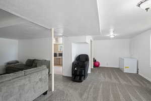 Living area with carpet floors, a textured ceiling, and baseboards