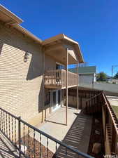 View of property exterior with brick siding, a patio area, a balcony, and french doors