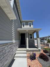 View of exterior entry with a porch and stone siding