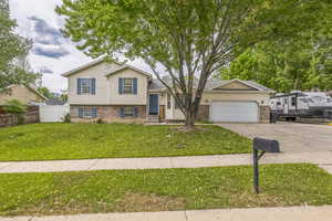 Tri-level home with brick siding, an attached garage, and concrete driveway