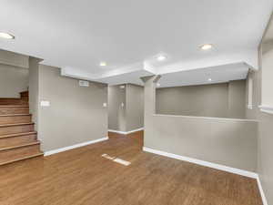 Finished below grade area featuring baseboards, wood finished floors, recessed lighting, and stairs