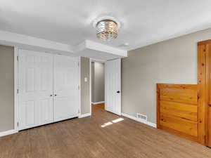 Unfurnished bedroom featuring wood finished floors, baseboards, and a closet