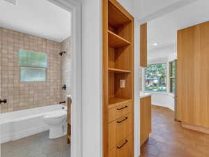 Hallway custom built in shelving.  Full bath with tile patterned flooring, vanity, toilet, tub / shower combination, and recessed lighting