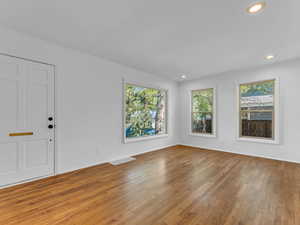 Unfurnished living room with wood finished floors, recessed lighting, and baseboards