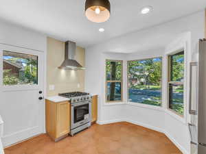 Kitchen featuring wall chimney exhaust hood, appliances with stainless steel finishes, plenty of natural light, light countertops, and recessed lighting