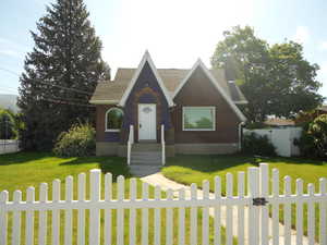 Tudor house featuring a gate, brick siding, and roof with shingles