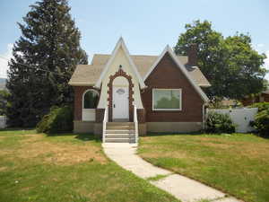 Tudor home with brick siding, a shingled roof, and a chimney