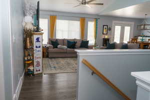 Living room featuring vaulted ceiling, dark wood-type flooring, and ceiling fan