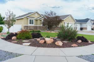 View of front of property with stucco siding, stone siding, and a garage