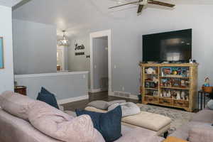 Living area with lofted ceiling, a ceiling fan, wood finished floors, and baseboards